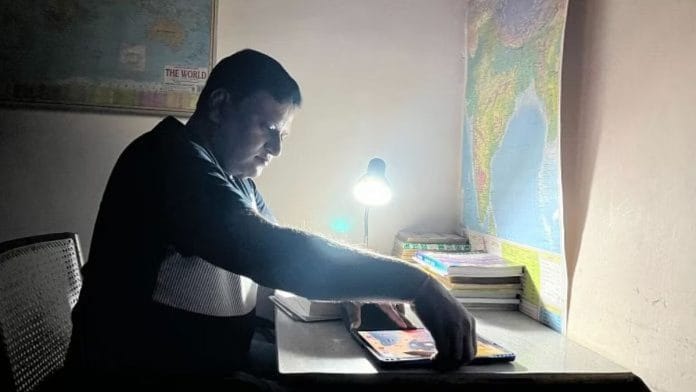पुष्पेंद्र श्रीवास्तव अपनी स्टडी डेस्क पर झुककर इंटरव्यू की तैयारी करते हुए | फोटो: नूतन शर्मा/दिप्रिंट
