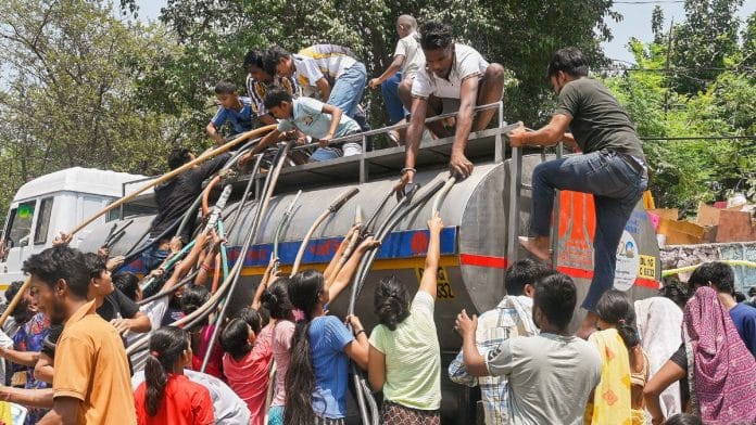 नई दिल्ली में जारी हीटवेव के बीच स्वामी विवेकानंद कैंप चाणक्यपुरी इलाके में पानी की समस्या के बाद नई दिल्ली नगर पालिका परिषद (एनडीएमसी) के पानी के टैंकर से एकत्र किए गए पीने के पानी को बाल्टी में भरकर ले जाते लोग | फोटो: एएनआई