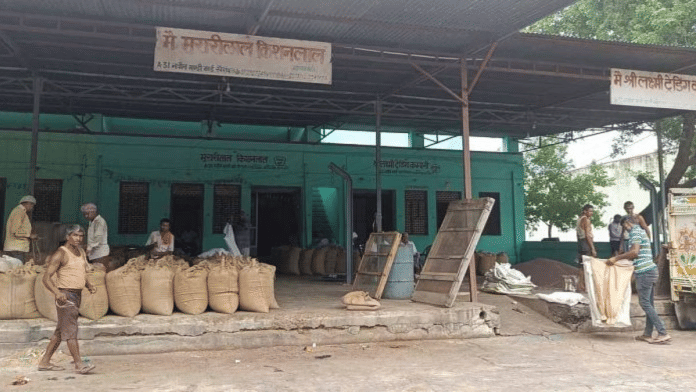 खैरथल अनाज मंडी में काम करने वाले लोग. जिला मजिस्ट्रेट का कार्यालय उसी जगह एक इमारत से संचालित होता है | फोटो: कृष्ण मुरारी/दिप्रिंट