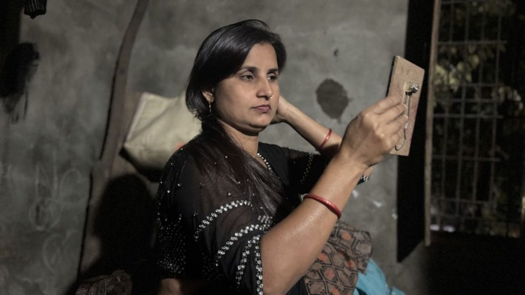 अपनी बाहों पर मॉइस्चराइजर लगाते हुए कहती हैं, ‘वो दिन भर शराब पीता है, काम नहीं करता और रात में मेरे साथ परफॉरमेंस के लिए आता है. वो मेरे पैसे से जीता है — और हमारे दो बच्चे भी’ | फोटो: प्रवीण जैन/दिप्रिंट